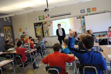 Samantha is teaching a class in a white and blue classroom; Caption: An action shot from one of my 6th grade German classes. On April Fool's Day, I 'pranked' the class by conducting it in Russian! Photo by Deirdre Abrahamsson of Wallingford Swarthmore School District.